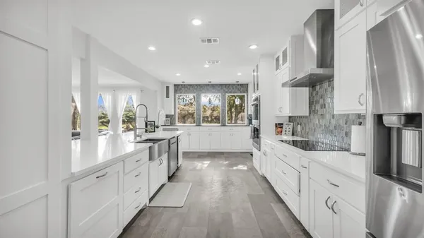 a large kitchen with stainless steel appliances kitchen island granite countertop a lot of counter space and wooden floors