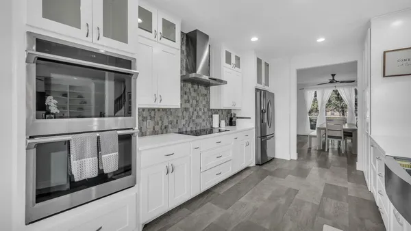 a kitchen with stainless steel appliances white cabinets and wooden floors