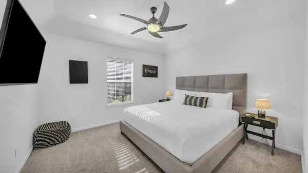 a bedroom with a bed a window and a flat screen tv