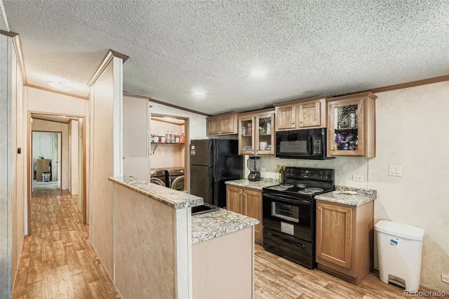 a kitchen with stainless steel appliances granite countertop a stove top oven a sink dishwasher and a refrigerator with wooden floor