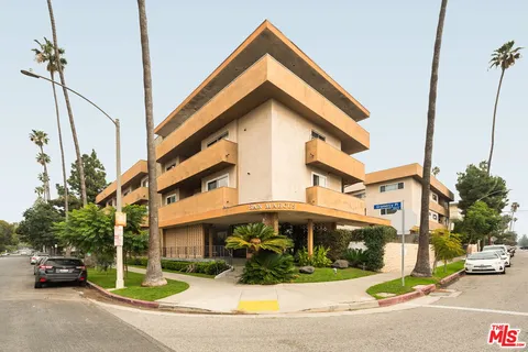 a view of a building with car parked on the road