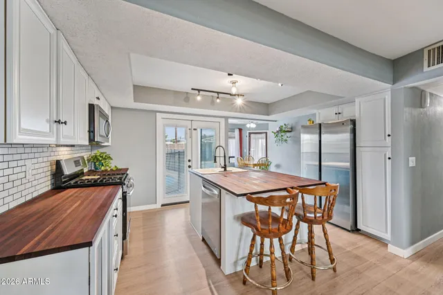 a kitchen with stainless steel appliances granite countertop a stove top oven a refrigerator a sink dishwasher and white cabinets with wooden floor