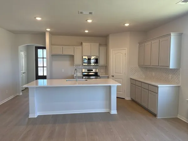 a large kitchen with stainless steel appliances a large counter top a stove and a refrigerator