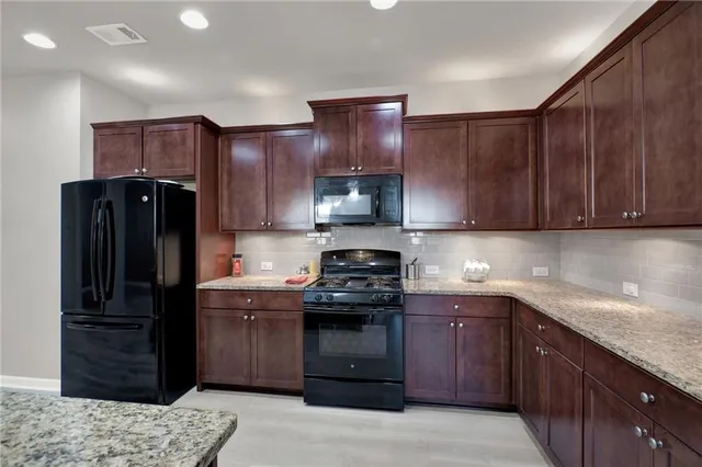 a kitchen with stainless steel appliances granite countertop a sink refrigerator and cabinets