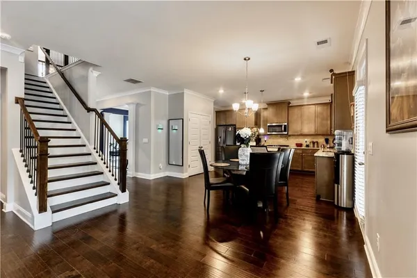 a view of a dining room and livingroom with furniture wooden floor a rug and a kitchen