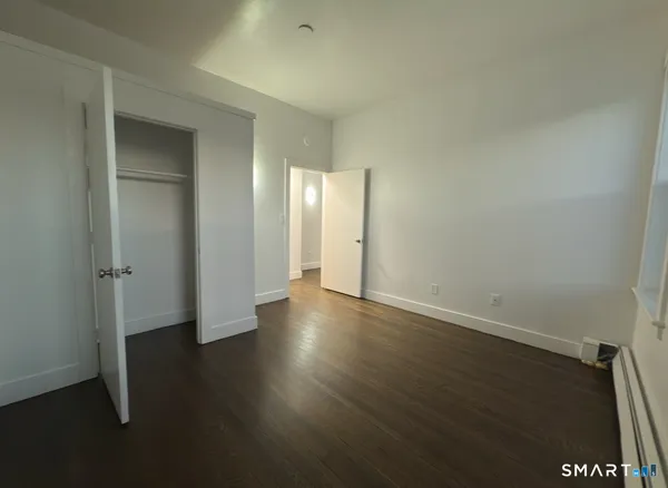 an empty room with wooden floor and closet area