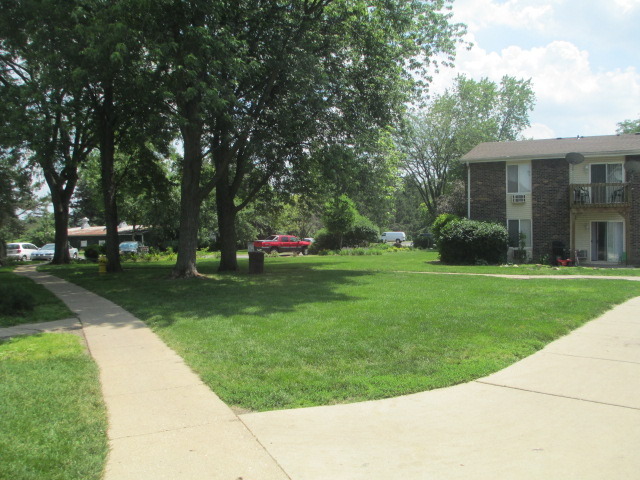 2600 Light Road, Unit 202 Oswego, IL 60543 - Photo 3 of 12 a view of a white house with a big yard and potted plants and large trees
