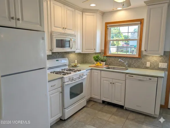 a kitchen with granite countertop white cabinets sink and white appliances