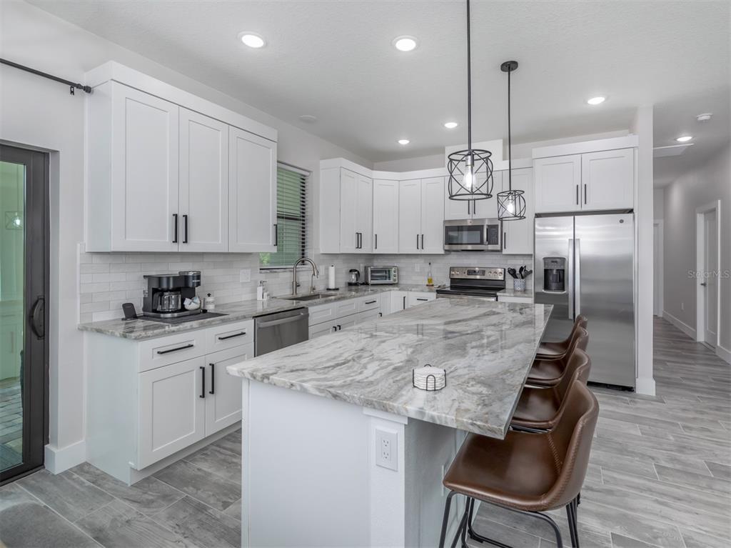17566 De Miranda Avenue North Port, FL 34287 - Photo 11 of 94 a kitchen with kitchen island granite countertop a counter space stainless steel appliances and cabinets