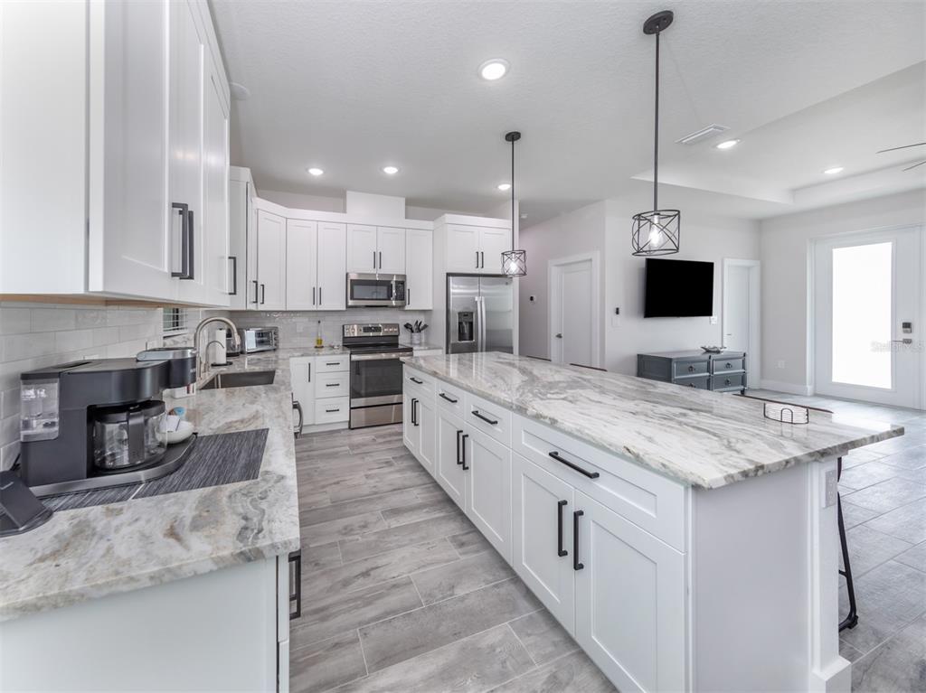 17566 De Miranda Avenue North Port, FL 34287 - Photo 12 of 94 a large kitchen with stainless steel appliances kitchen island granite countertop a large counter top a stove a sink and a refrigerator