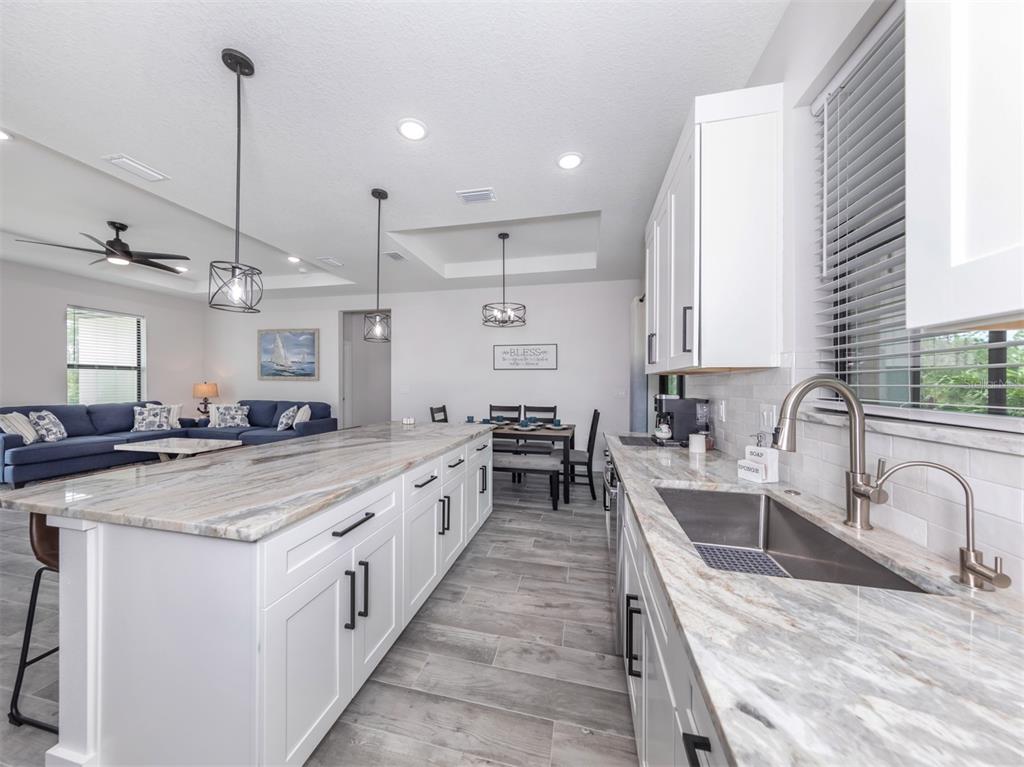 17566 De Miranda Avenue North Port, FL 34287 - Photo 14 of 94 a kitchen with stainless steel appliances granite countertop a sink a stove and a wooden floors