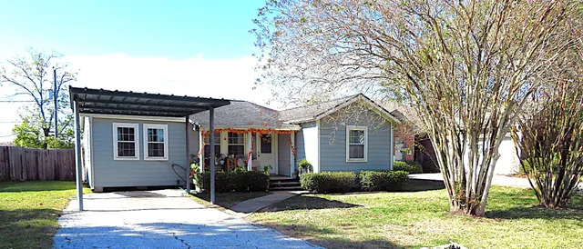 a front view of a house with yard and tree