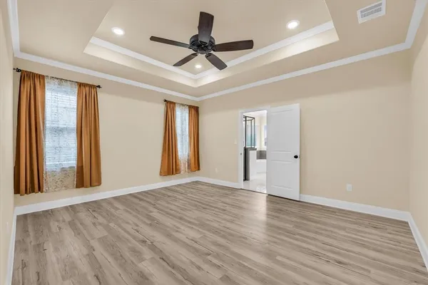 a view of an empty room with a window and wooden floor