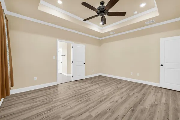 an empty room with wooden floor and a ceiling fan