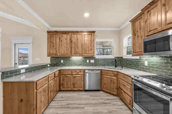 a kitchen with stainless steel appliances granite countertop wooden cabinets a sink dishwasher a stove and a refrigerator