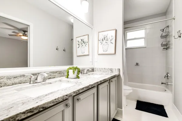 a bathroom with a granite countertop sink a mirror a bathtub and shower