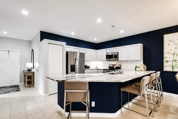 a large kitchen with kitchen island granite countertop a sink a counter top space and stainless steel appliances