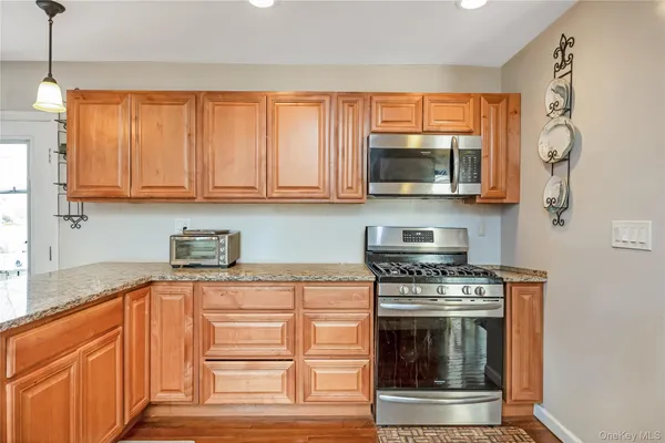 a kitchen with granite countertop a stove top oven cabinetry a sink and a microwave