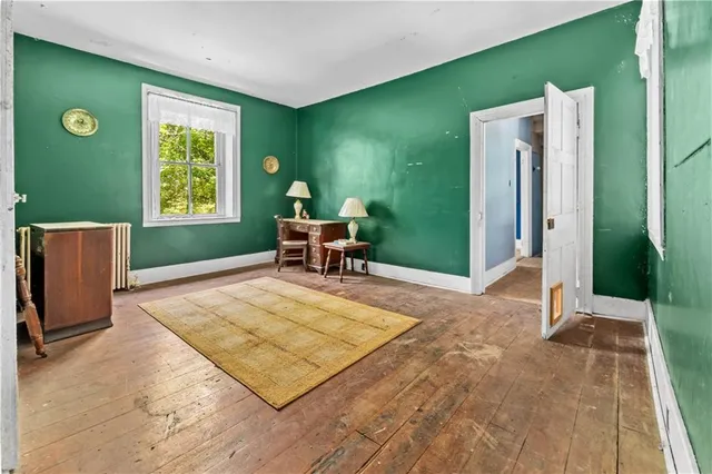 a view of an empty room with a window and wooden floor