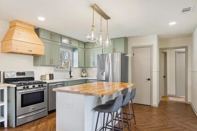 a kitchen with stainless steel appliances a stove a refrigerator and a kitchen island