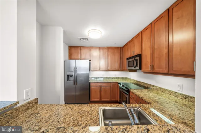 a kitchen with stainless steel appliances granite countertop a refrigerator a sink and a stove