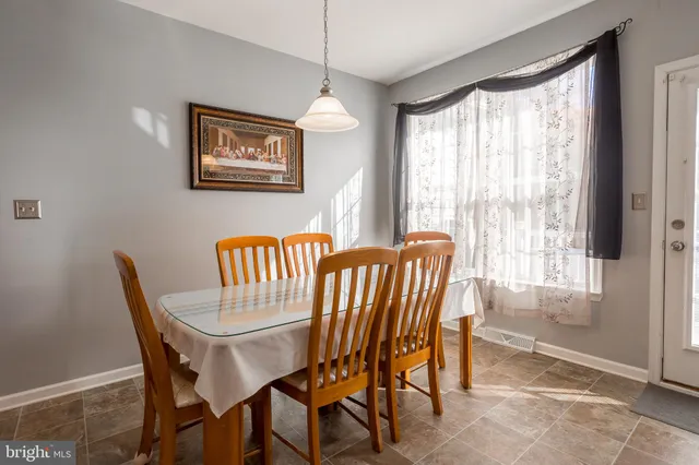 a kitchen with stainless steel appliances kitchen island granite countertop a refrigerator a stove a sink a dining table and chairs with wooden floor