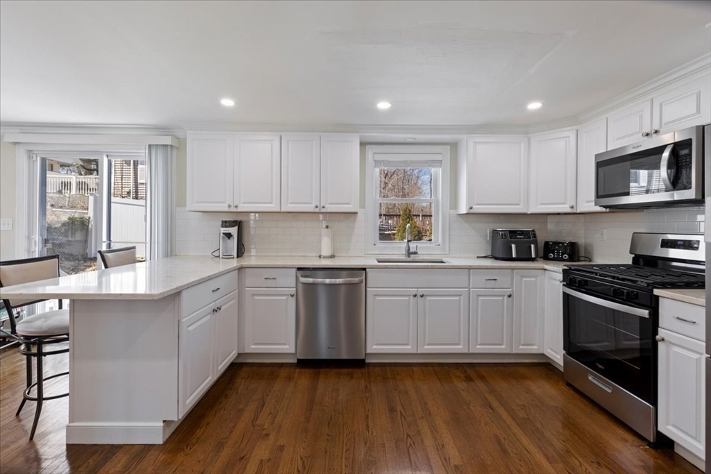 19 Warren Avenue Saugus, MA 01906 - Photo 2 of 33 a kitchen with stainless steel appliances granite countertop wooden cabinets a sink a stove a microwave and wooden floors
