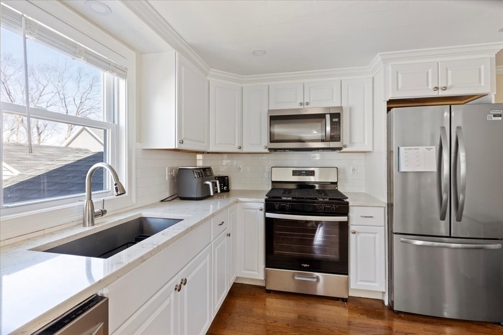 19 Warren Avenue Saugus, MA 01906 - Photo 5 of 33 a kitchen with stainless steel appliances a stove a sink a refrigerator a window and cabinets