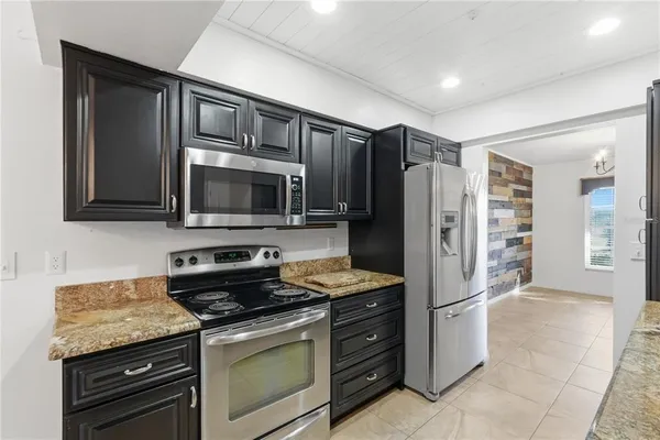 a kitchen with granite countertop a refrigerator stove and microwave