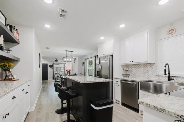 a kitchen with stainless steel appliances kitchen island granite countertop a sink a stove and a refrigerator