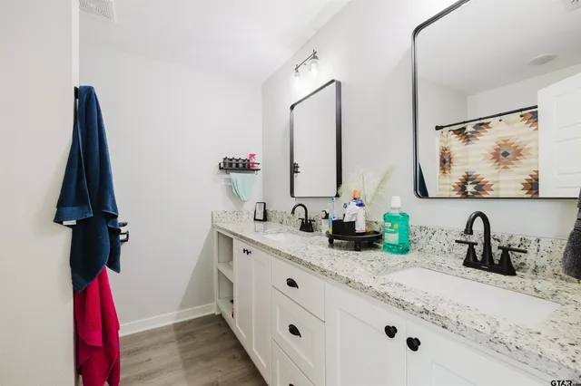a bathroom with a double vanity sink and mirror with bathtub