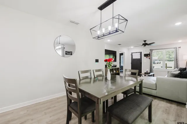 a dining room with wooden floor a chandelier a wooden table and chairs