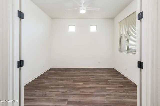 a view of an empty room with wooden floor and a window