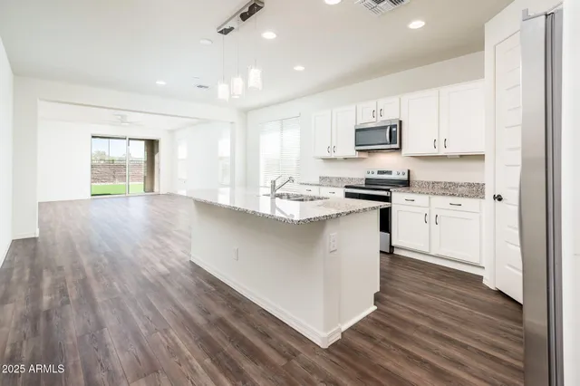 a kitchen with stainless steel appliances granite countertop a stove top oven a sink dishwasher and a refrigerator with wooden floor