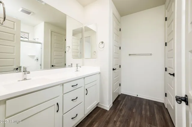 a spacious bathroom with a double vanity sink a mirror and a shower
