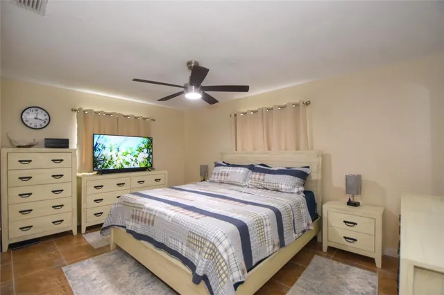 a bedroom with a bed and a flat tv screen on dresser