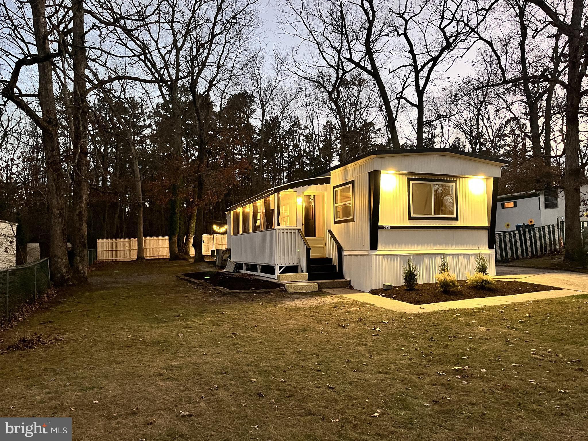 a front view of a house with a yard covered with snow and trees