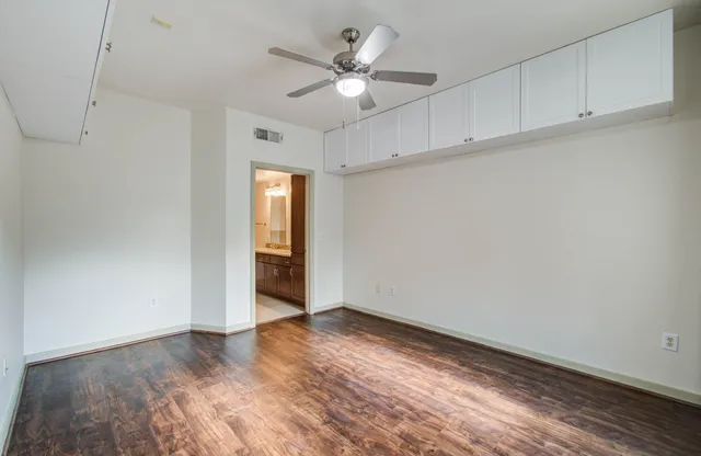 a view of an empty room with cabinet and a ceiling fan