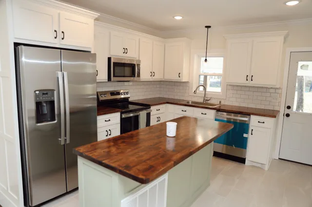 a kitchen with stainless steel appliances granite countertop a refrigerator a sink and a stove