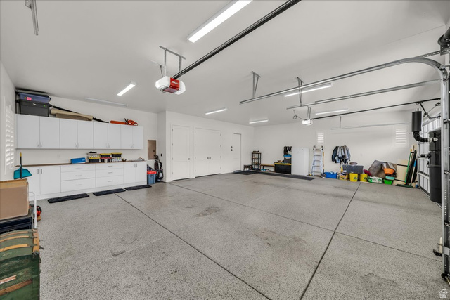 2608 Canyon Ridge Drive St. George, UT 84770 - Photo 44 of 86 Spacious garage featuring a durable epoxy-coated concrete floor, extensive built-in white cabinetry with a wood-finish countertop, fluorescent lighting, and two overhead garage door openers