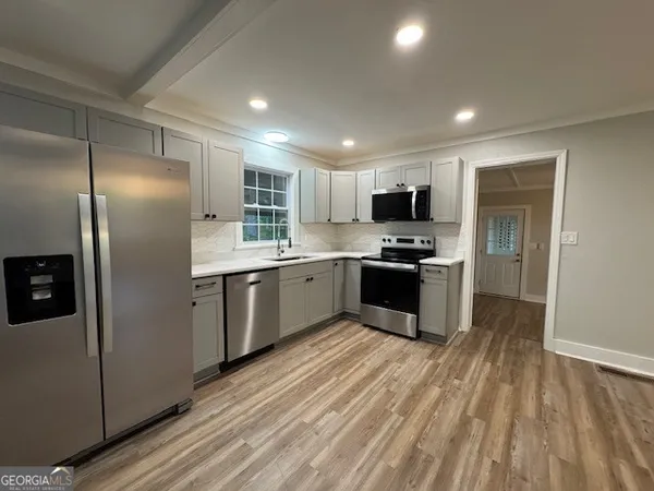a kitchen with granite countertop a refrigerator and stainless steel appliances