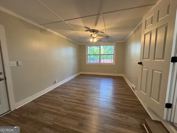 an empty room with wooden floor fan and windows