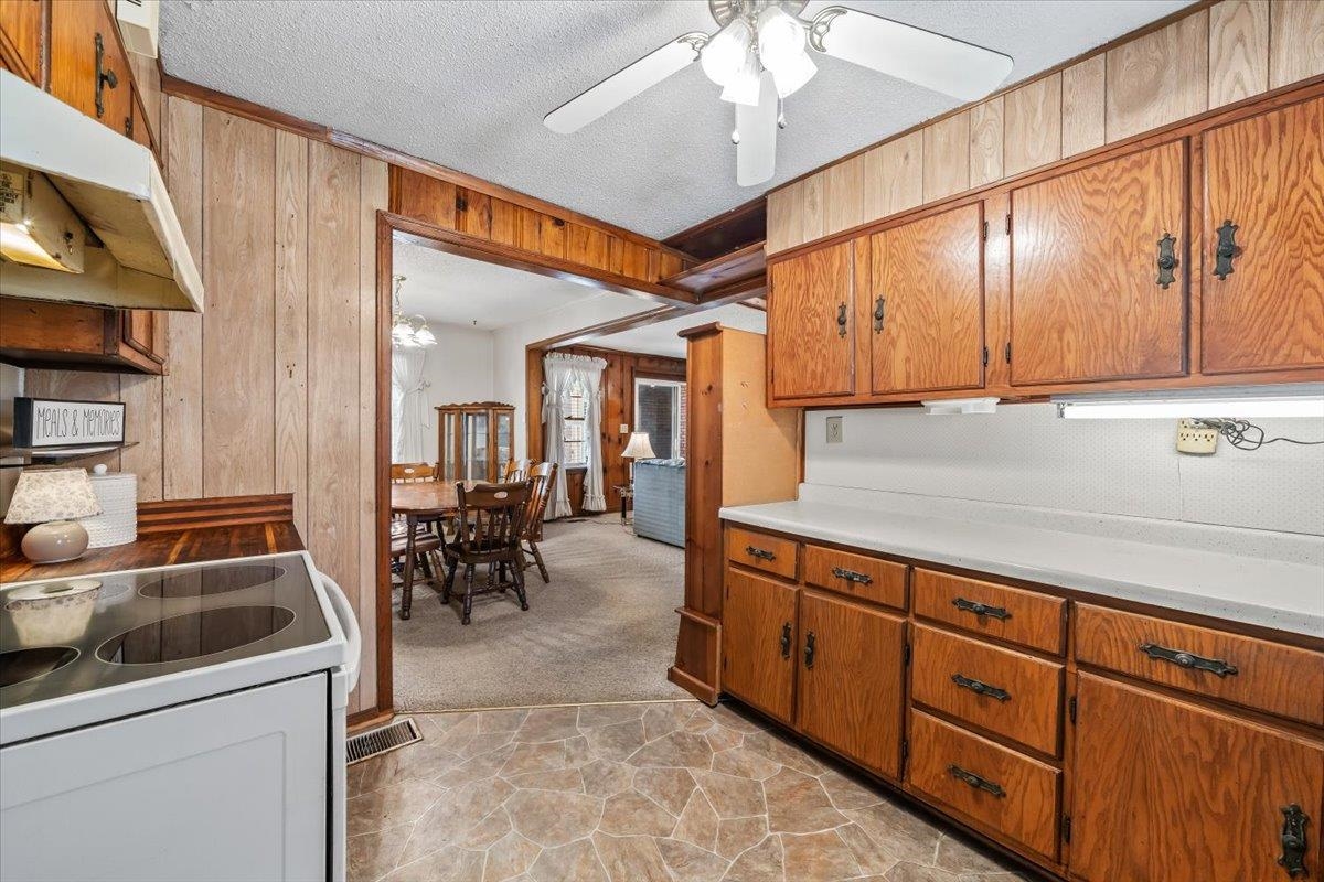 2972 Russell Bond Road Millington, TN 38053 - Photo 30 of 38 Kitchen with light countertops, wood finish cabinets, wooden walls, a textured ceiling, and range with electric cooktop