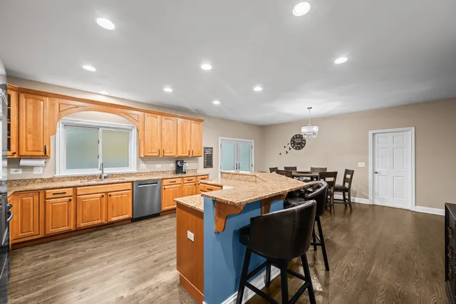 a kitchen with stainless steel appliances granite countertop table chairs sink and cabinets