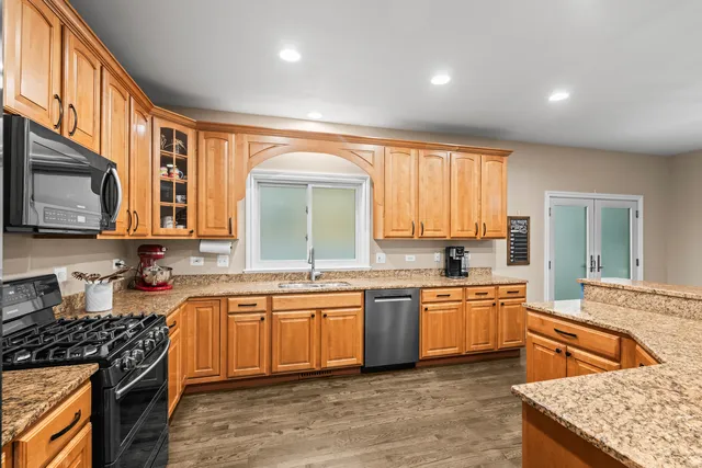 a kitchen with stainless steel appliances granite countertop wooden cabinets and a stove top oven