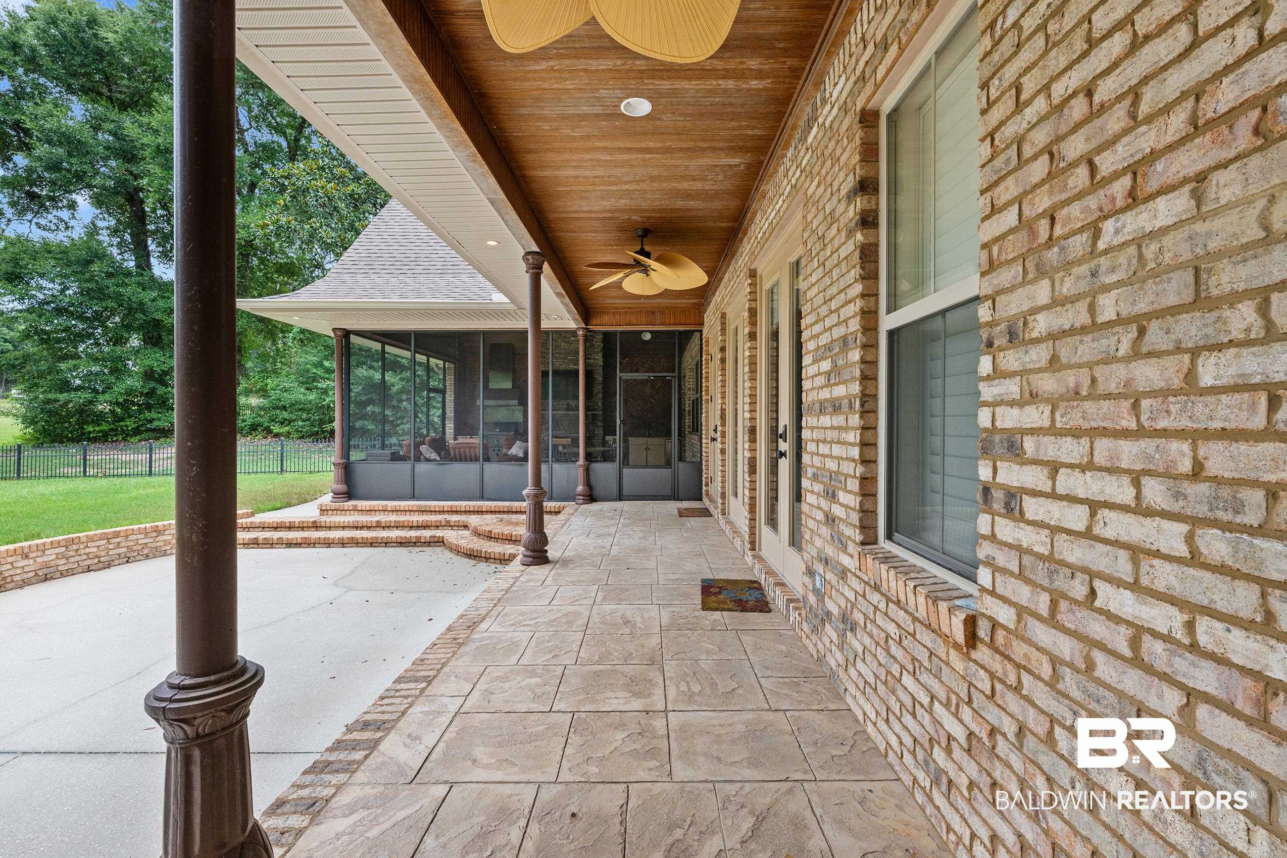 30463 Dolive Ridge Daphne, AL 36527 - Photo 18 of 58 Exterior stone-look tile patio extending to a concrete pad, bordered by a brick knee wall