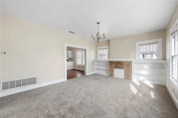an empty room with chandelier and fireplace