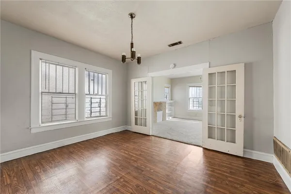 a view of an empty room with a window and wooden floor