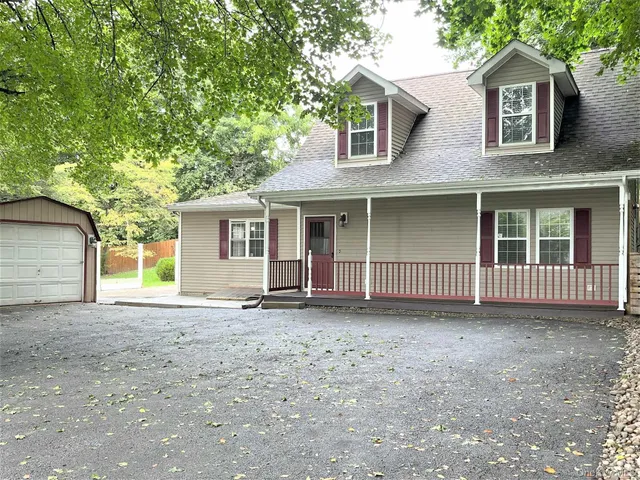 a view of a house with a yard and large tree
