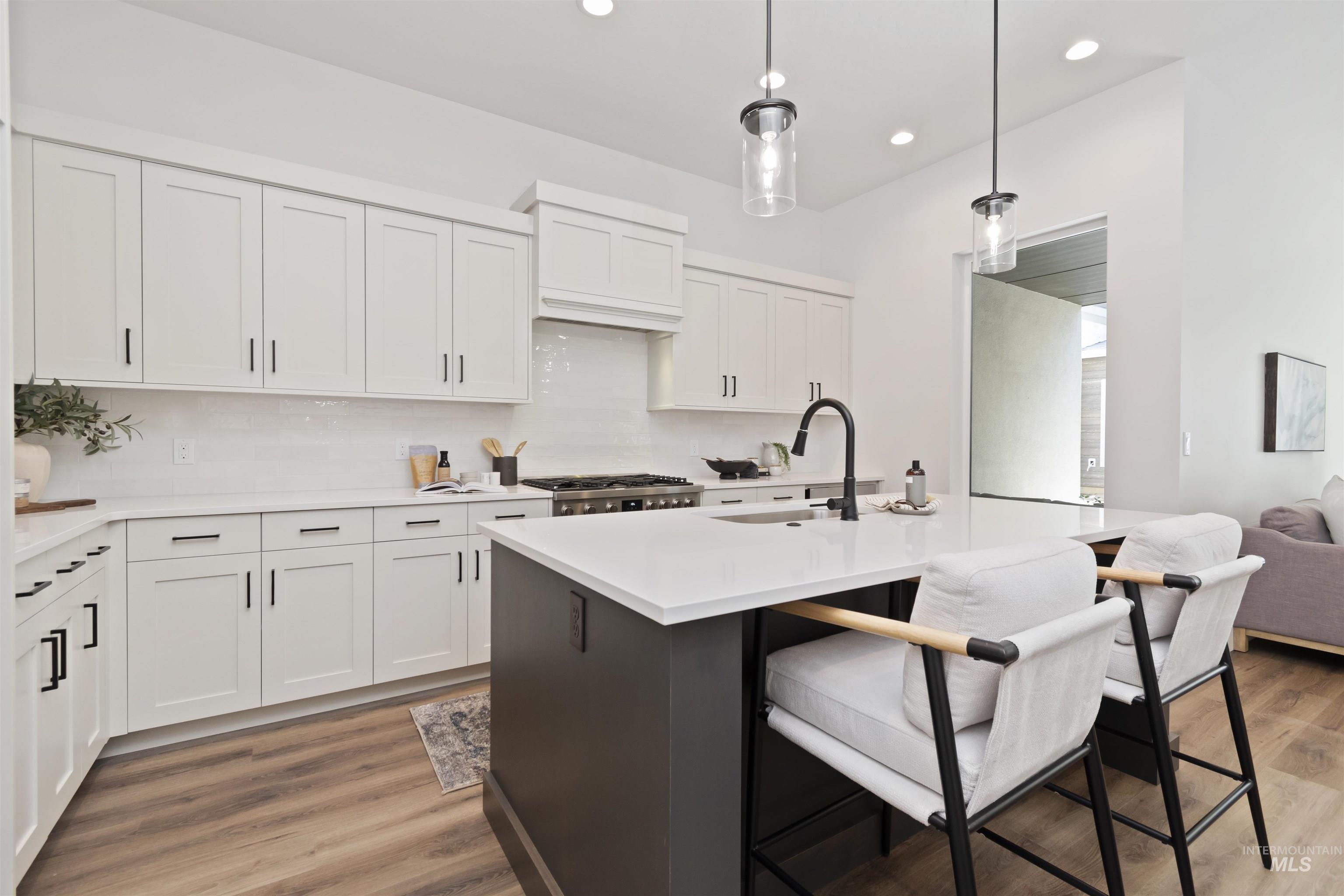 724 South Calhoun Lane Star, ID 83669 - Photo 11 of 46 Kitchen featuring white cabinetry, decorative light fixtures, a center island with sink, tasteful backsplash, and recessed lighting